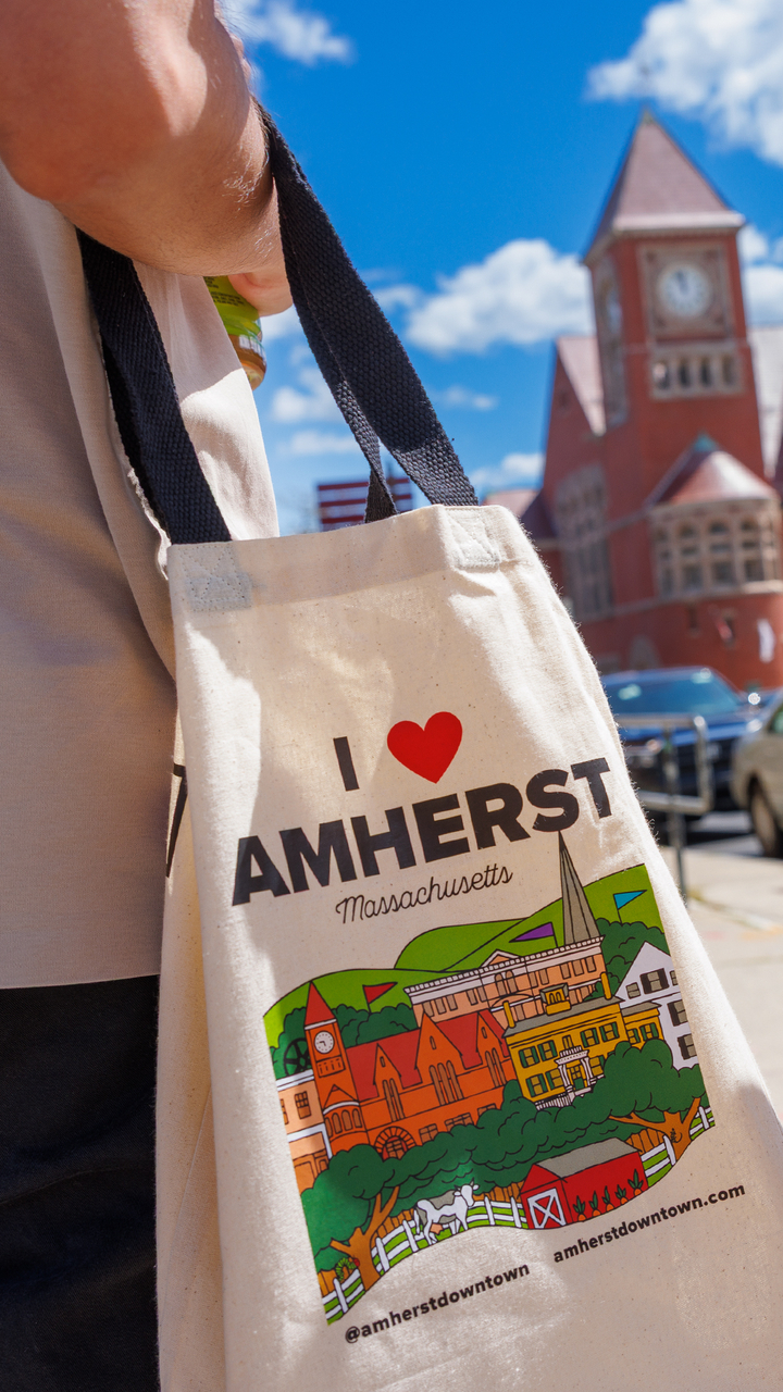 A UMass student holds a hote bag that reads "I Love Amherst."